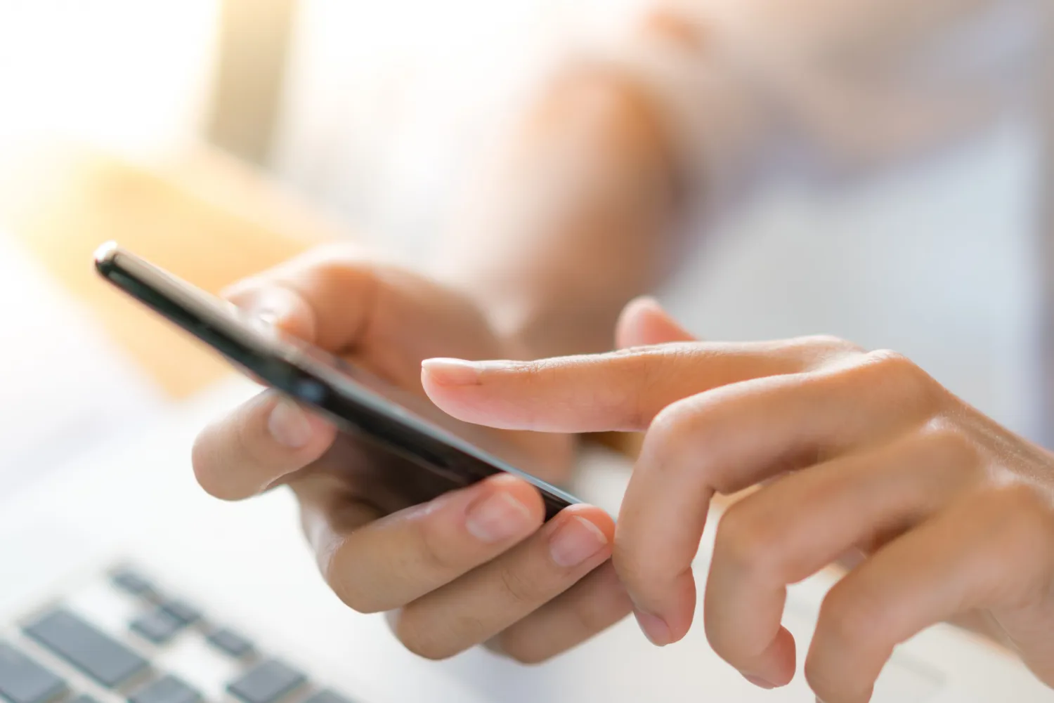 Mano donna telefono cellulare su laptop sul tavolo.