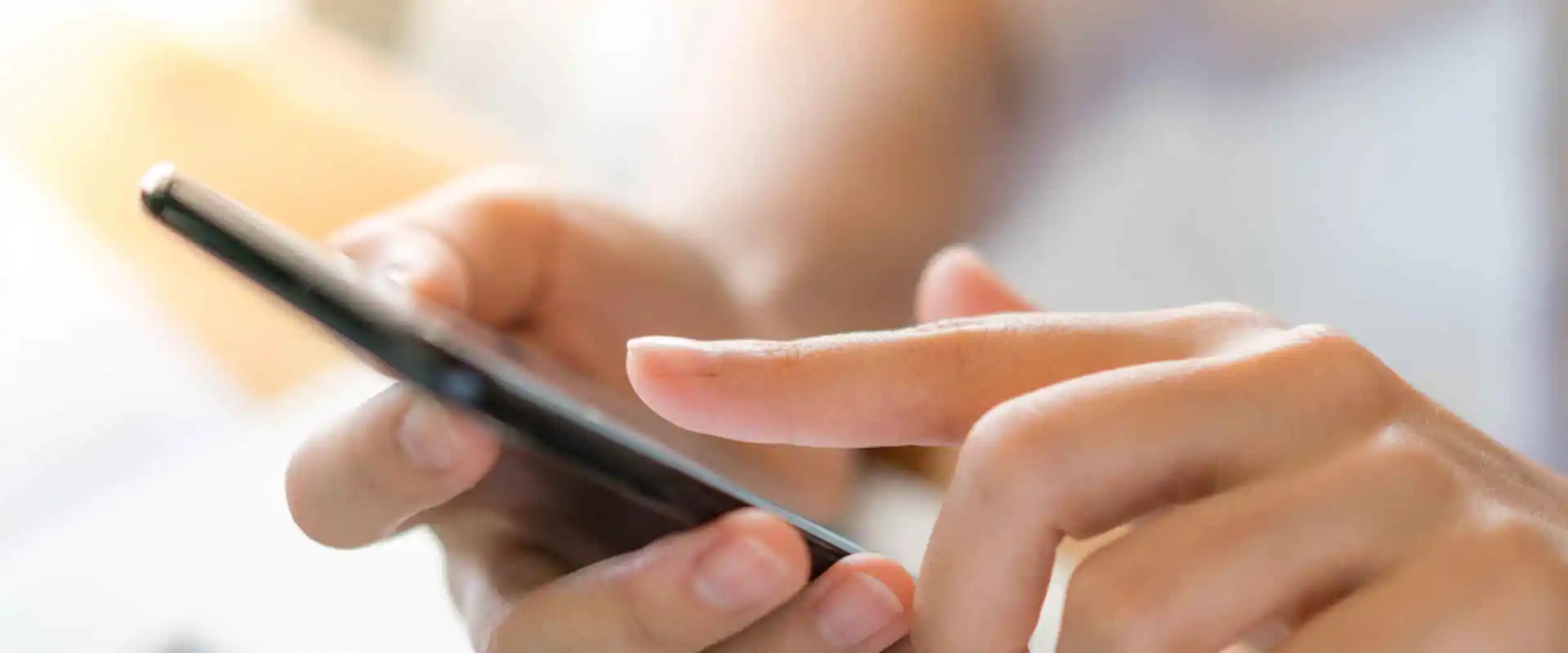 Mano donna telefono cellulare su laptop sul tavolo.